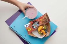 A student holding a smoothie sitting next to a CinnaFuego Toast Crunch Bar